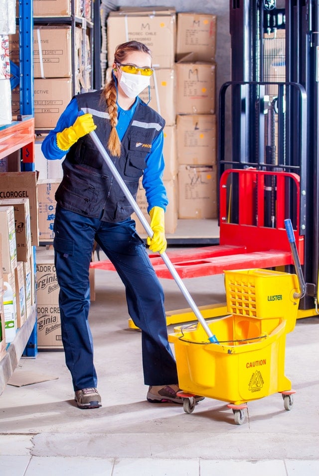 Woman with a mop and bucket wearing a mask - maintenance - San Francisco Audiology