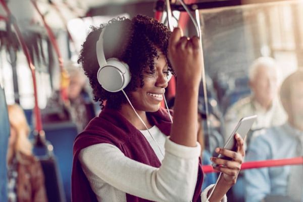 A person smiling and wearing over-the-ear headphones on a bus