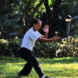 older man doing tai chi in a grassy area
