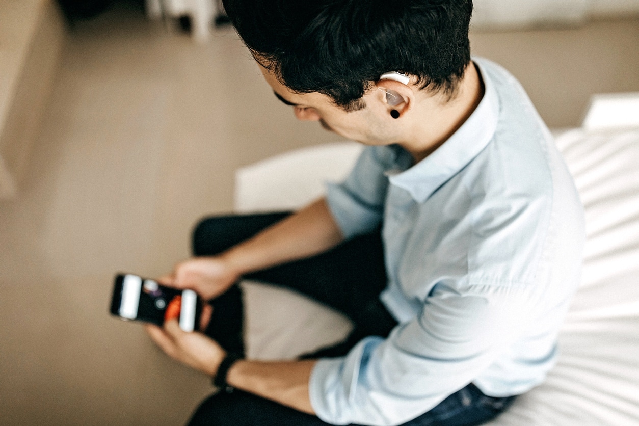 Relaxed Businessman Using Phone in Hotel Room with a hearing aid in