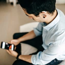 Younger man with a hearing aid using his smartphone.