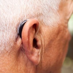 Older man wearing a behind-the-ear hearing aid.