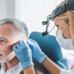 Man with hearing problem having his ears examined by a medical professional.