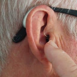 Close up of an older man adjusting his hearing aid.