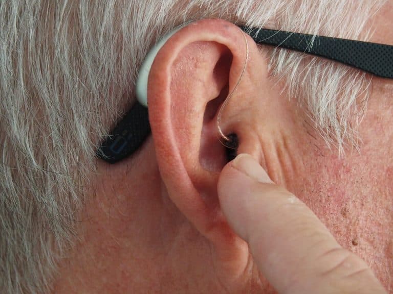Close up of an older man adjusting his hearing aid.