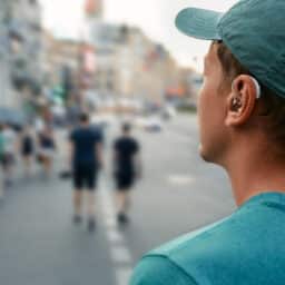 Young man with a hearing aid walking around a busy city.