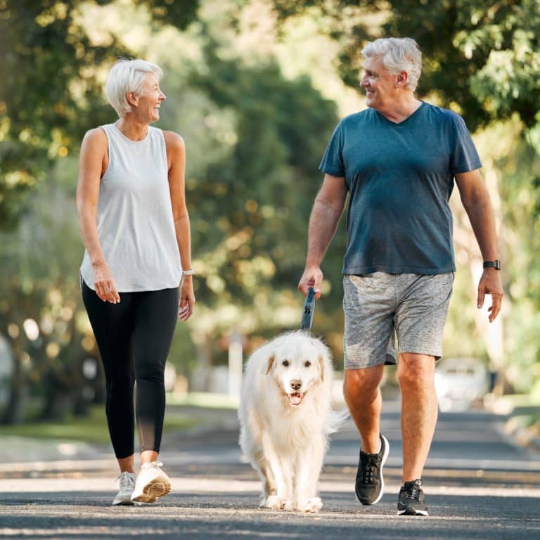 two people walk outside with a dog in between them