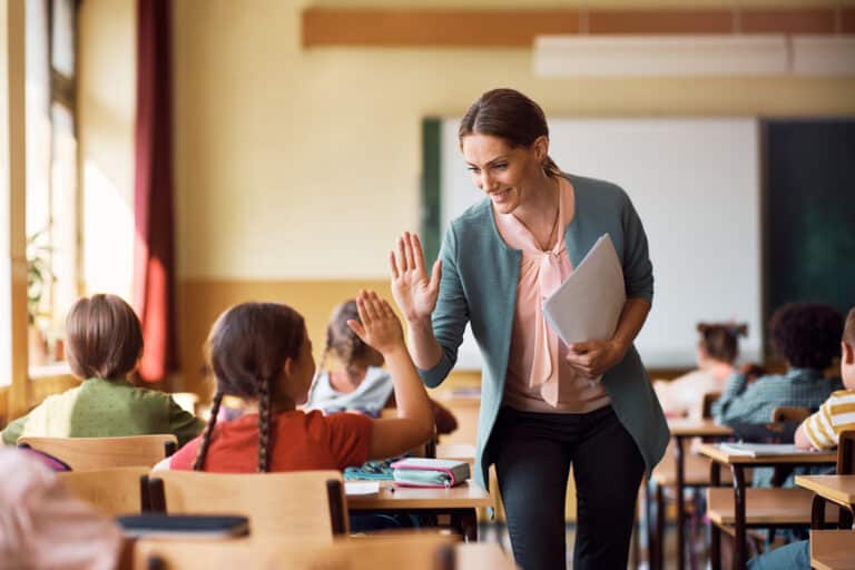 Student high-fiving her teacher in a classroom