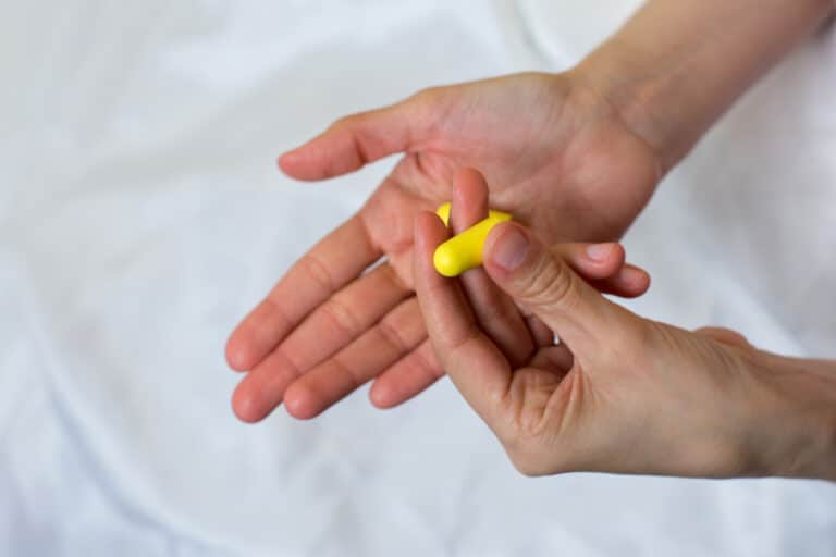 Close-up of hands holding earplugs.