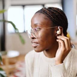 Woman adjusts hearing aid behind ear