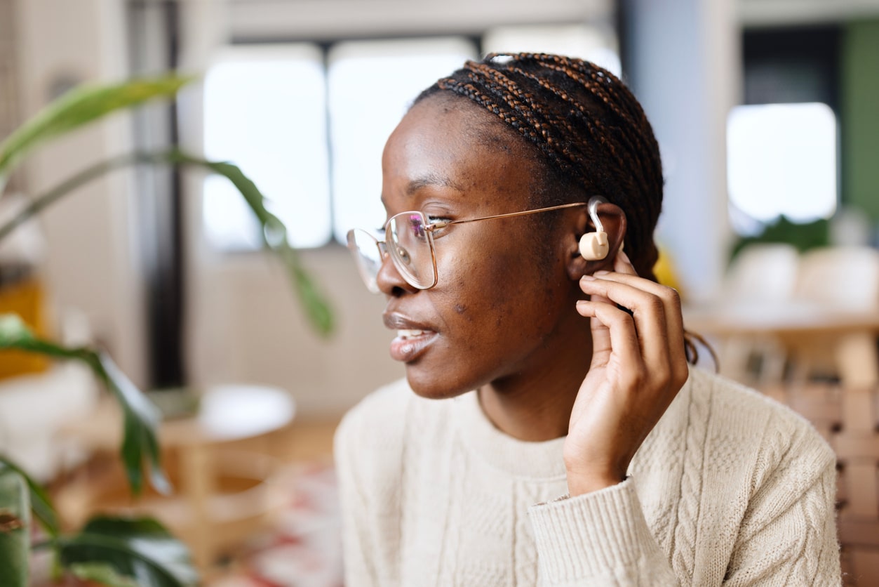 Woman adjusts hearing aid behind ear