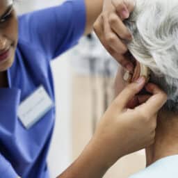 Audiologist checking her patient's hearing aid
