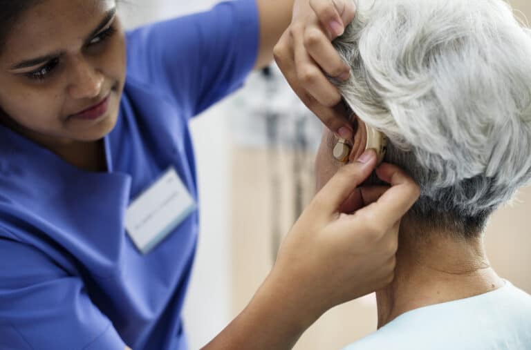 Audiologist checking her patient's hearing aid