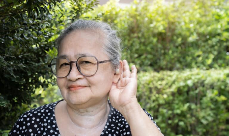 Woman holds hand behind ear to hear