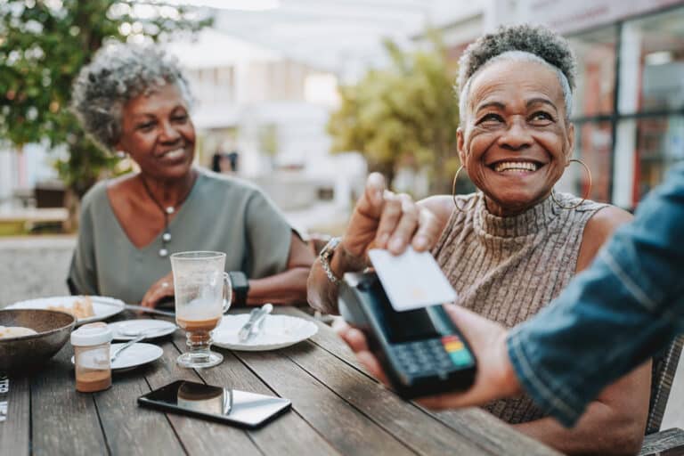 Senior woman and her friend paying for dinner at a restaurant 