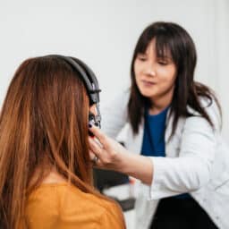 Audiologists putting headphones on a woman for a hearing test