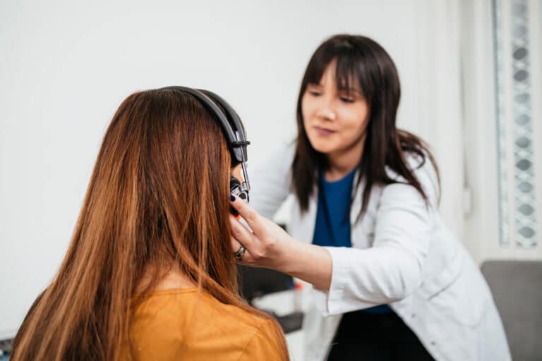 Audiologists putting headphones on a woman for a hearing test