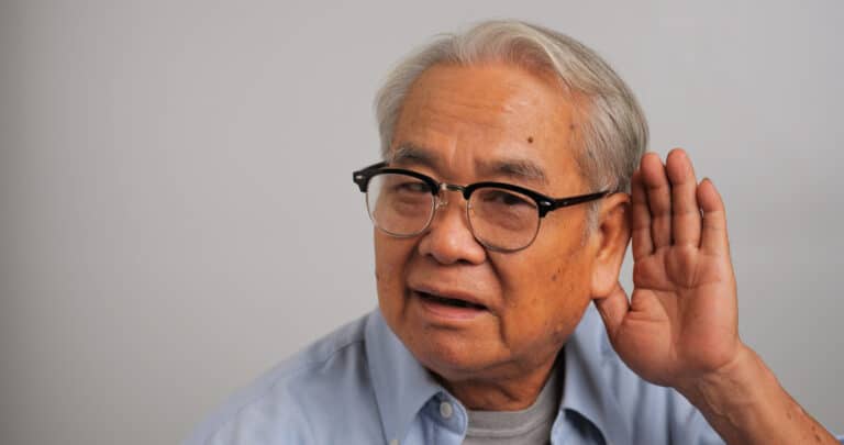 Man with hearing loss holds hand behind ear
