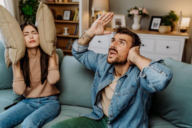 A couple covering their ears to block out noise